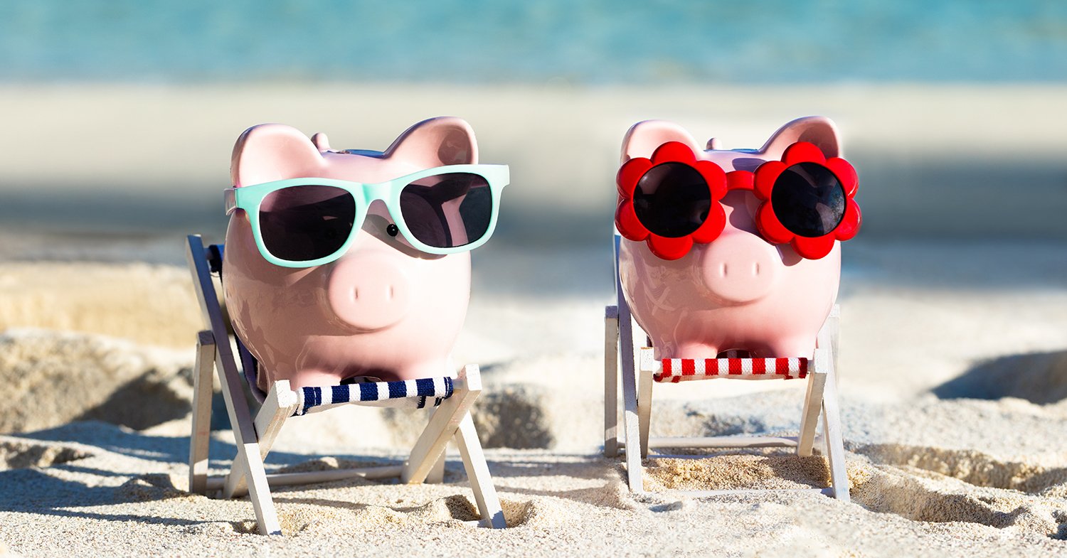 Two piggy banks relaxing on the beach