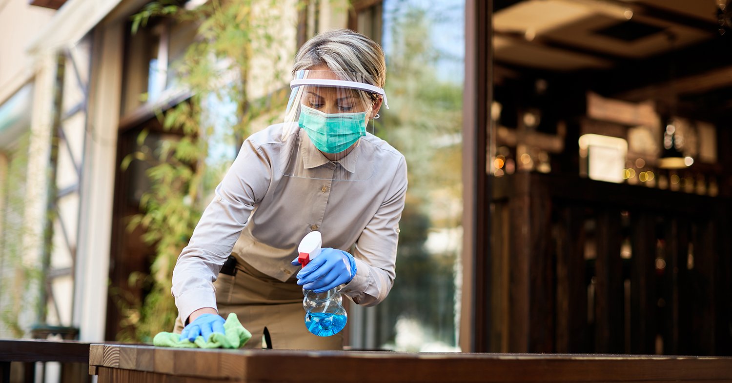 Woman cleaning table outside of restaurant