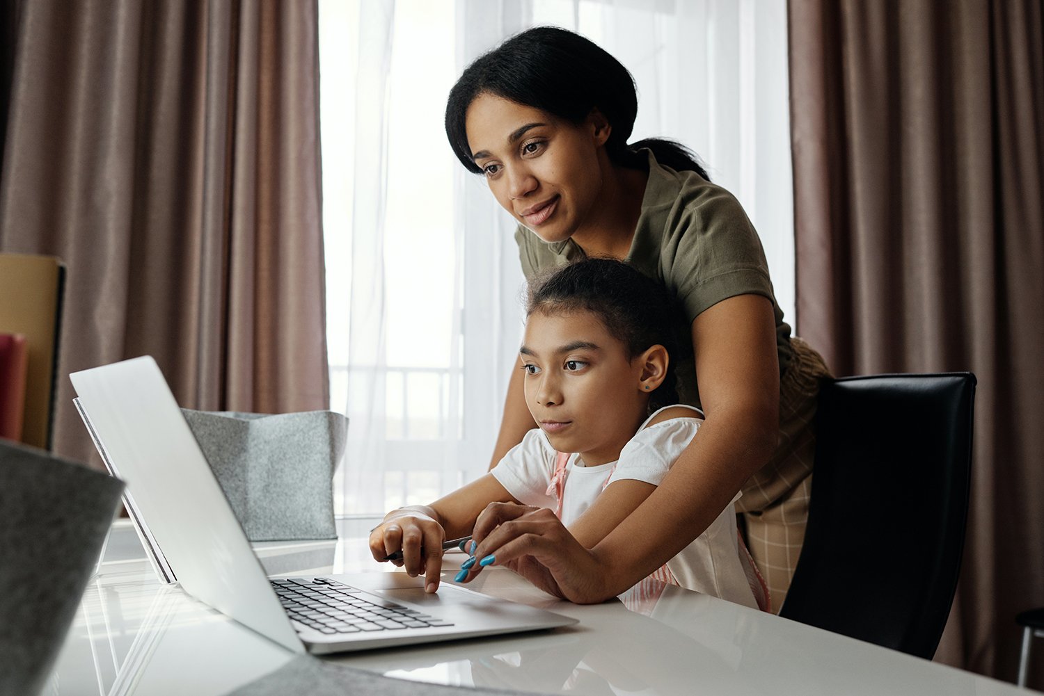 Mom helping daughter with work on laptop
