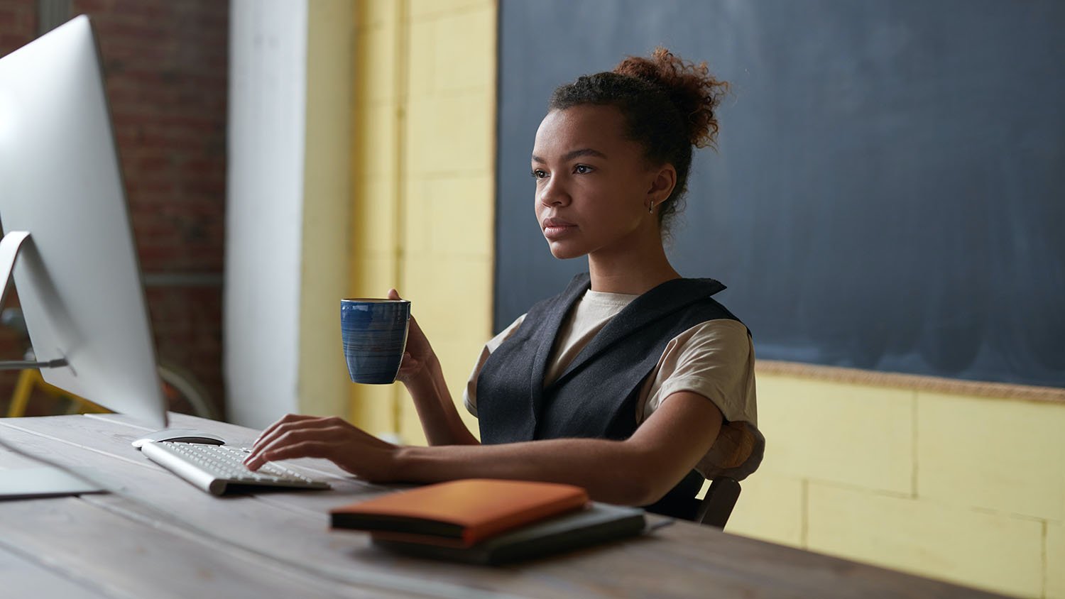 Woman sitting at computer holding coffee mug